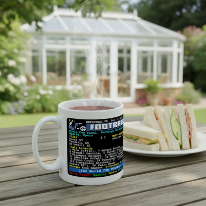 Retrotext 11oz glossy white mug featuring 1982 Italy World Cup final teletext score, sitting on a wooden garden table.