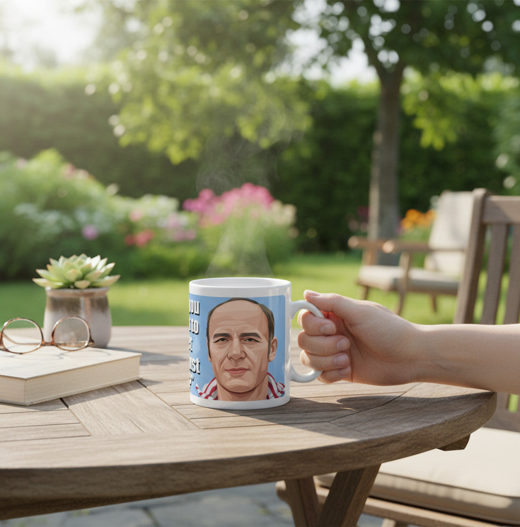 Retrotext Aston Villa 1981 Ron Saunders mug held in a hand on a wooden garden table with a book and glasses nearby.