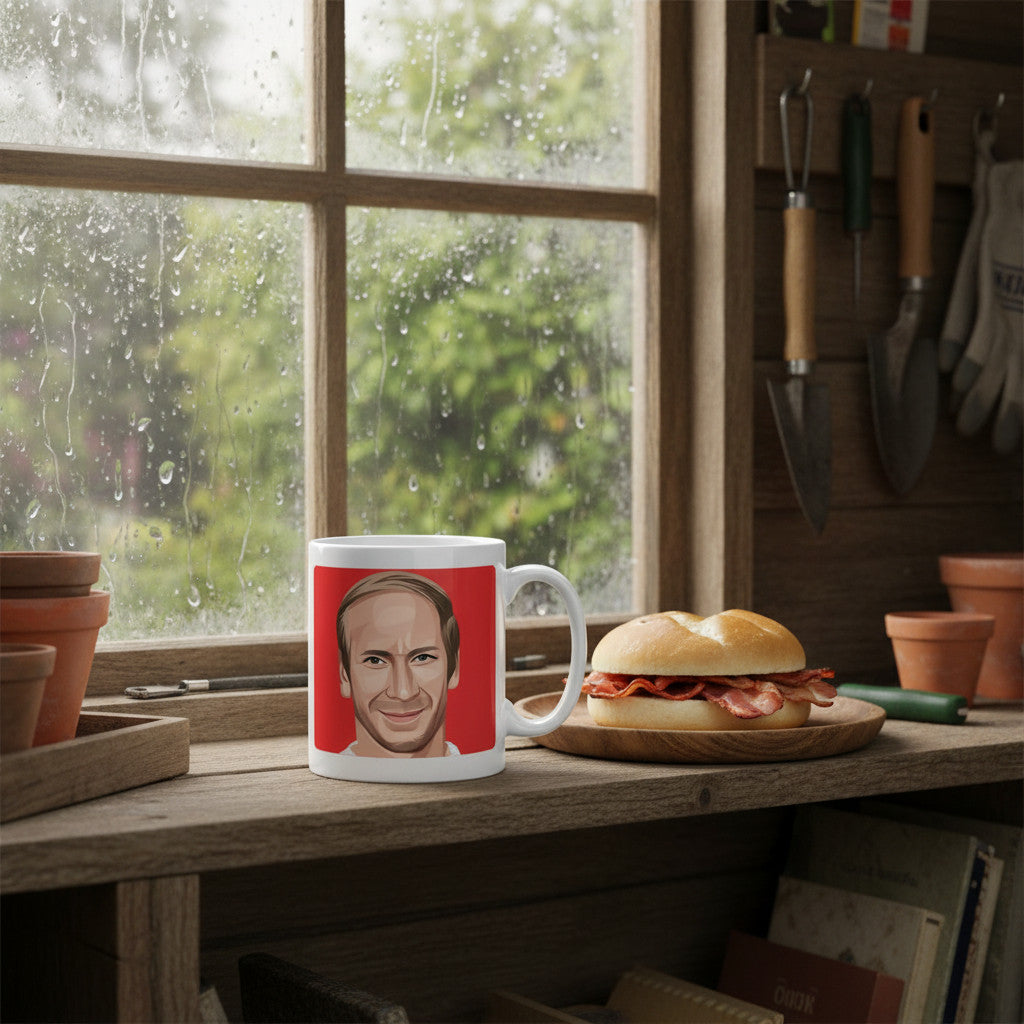 Retrotext 11oz glossy white mug featuring a Bobby Charlton illustration on a red background by a rainy window