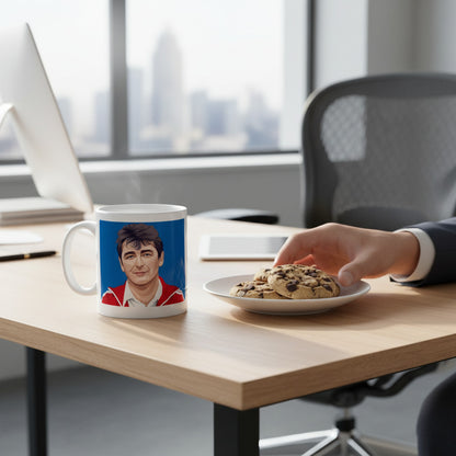 Retrotext 11oz glossy white mug featuring a Brian Clough illustration on a desk with a plate of chocolate chip cookies