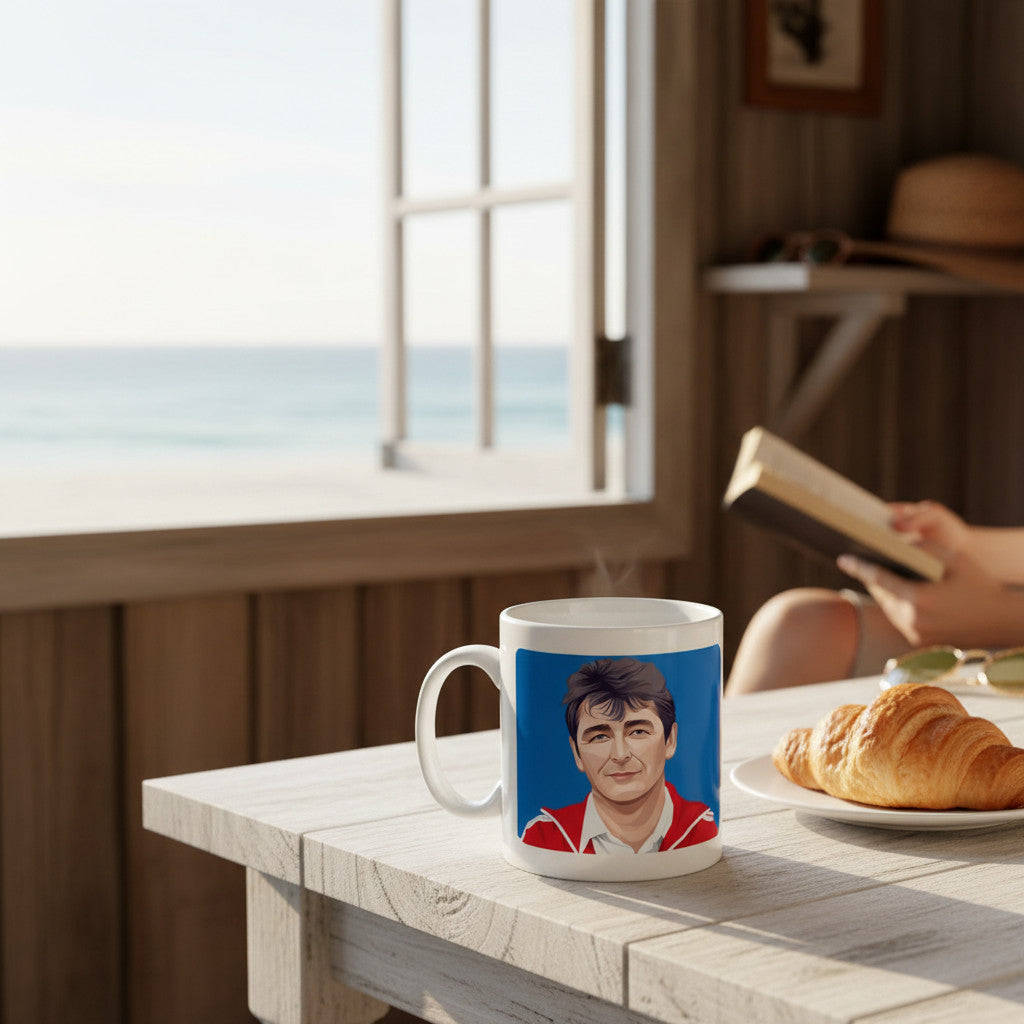 Retrotext 11oz glossy white mug featuring a portrait of Brian Clough, set on a wooden table by a sunny seaside window.