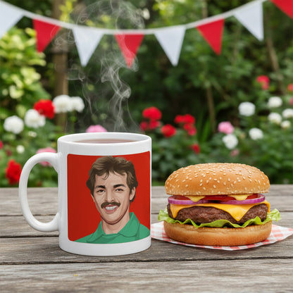 Retrotext 11oz glossy white ceramic mug featuring a Bruce Grobbelaar illustration, set on a wooden table with a burger
