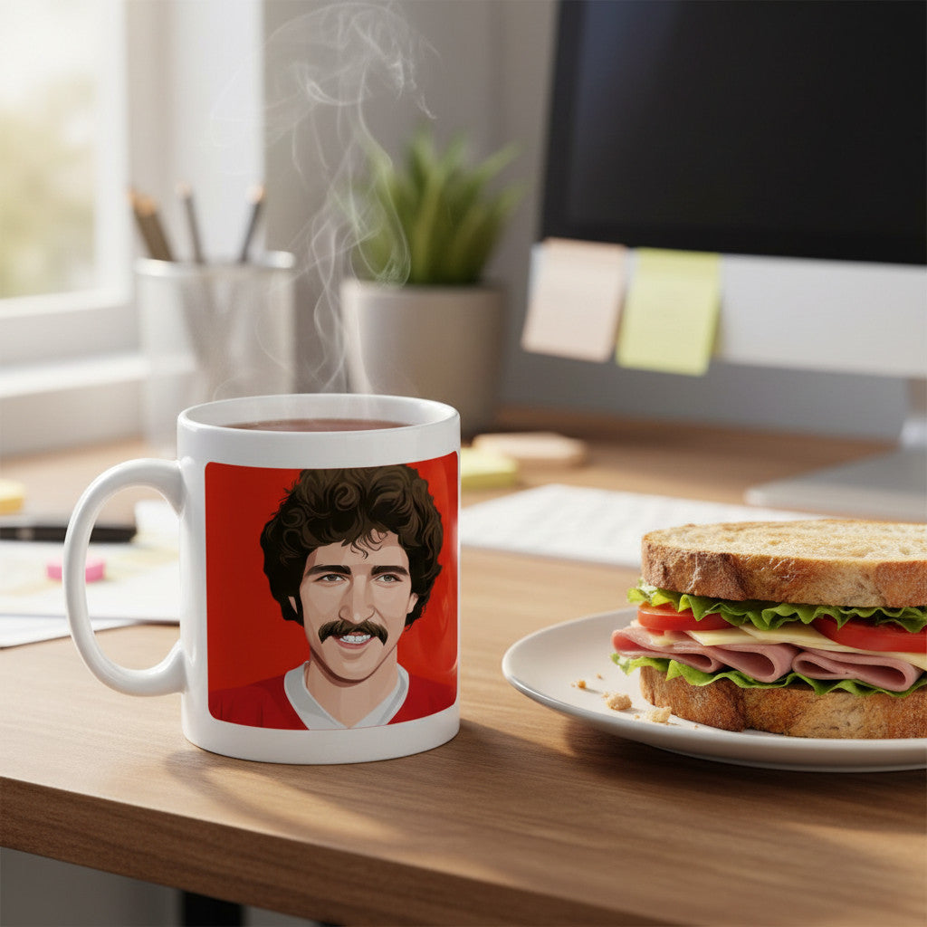 Retrotext 11oz glossy white mug featuring a graphic of Graeme Souness on a red background, sitting on a desk.
