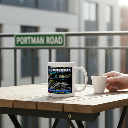 Retrotext Ipswich Town 2000 playoff semi-final ceramic mug with teletext design on a balcony table with a Portman Road sign