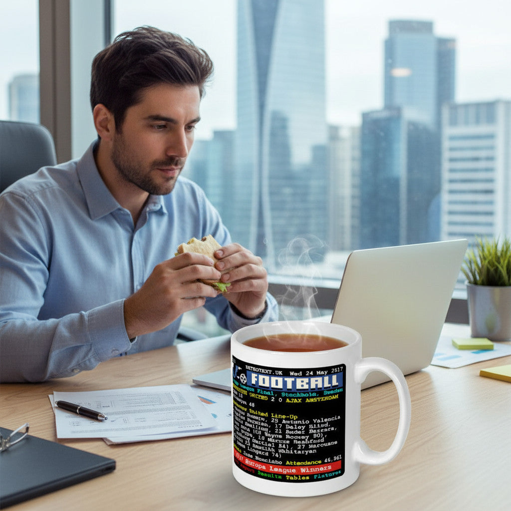 Retrotext Manchester United 2017 Europa League Winners ceramic mug with teletext design on a desk with a man eating.