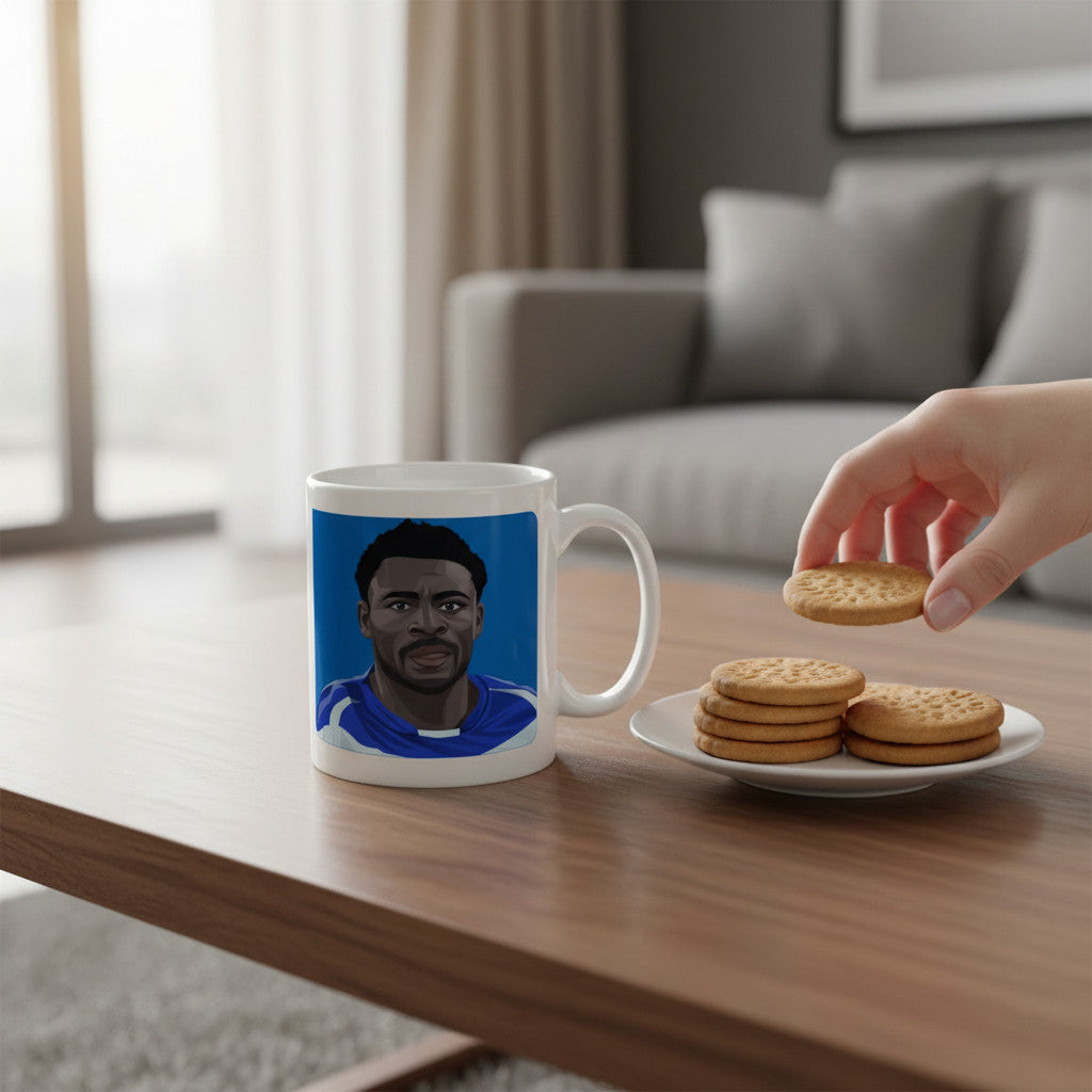 Retrotext ceramic mug featuring Obafemi Martins illustration on a wooden table with a plate of biscuits