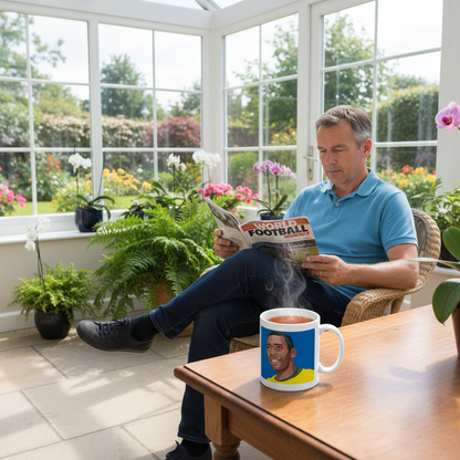 Retrotext 11oz glossy white mug featuring a Pele illustration, sitting on a table next to a man reading a magazine.