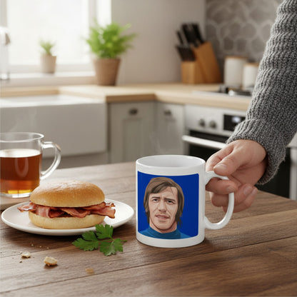 Retrotext Rangers 1972 John Greig ceramic mug featuring a blue teletext-style illustration on a wooden kitchen table.