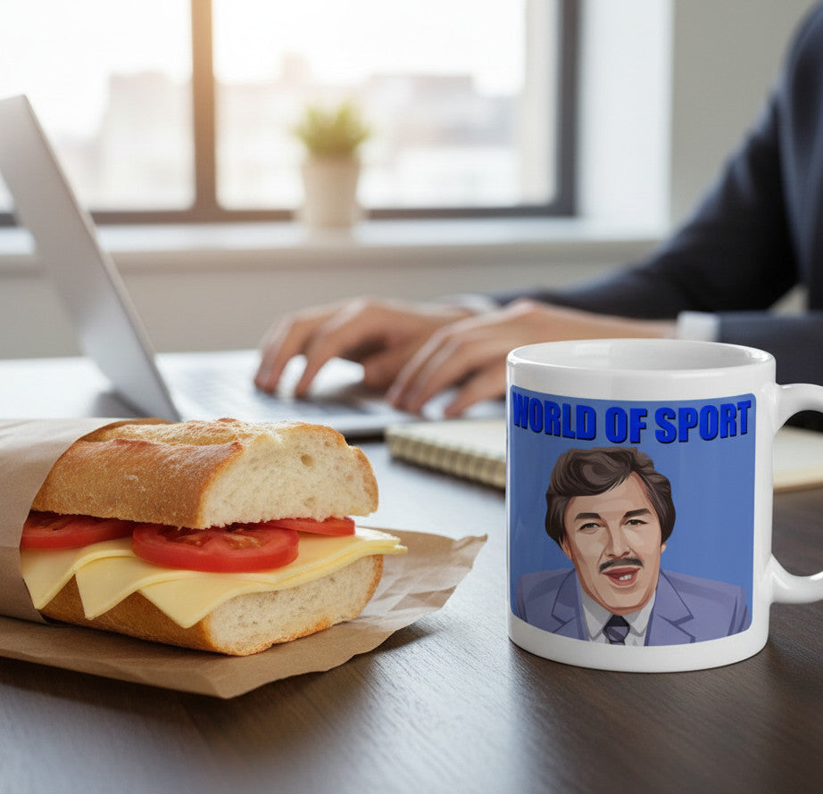 Retrotext white ceramic mug featuring a World Of Sport graphic on a desk next to a sandwich and laptop